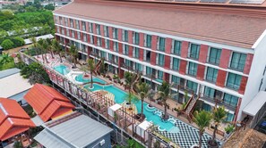 A multi-story hotel with a rooftop pool area, including a main pool and a children's pool.