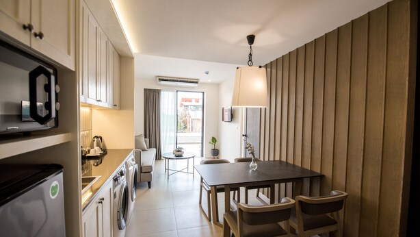 A modern kitchen with a dining area, built-in appliances, and a view to the outside. - Marina House MUAYTHAI Ta-iad Phuket (Chalong)