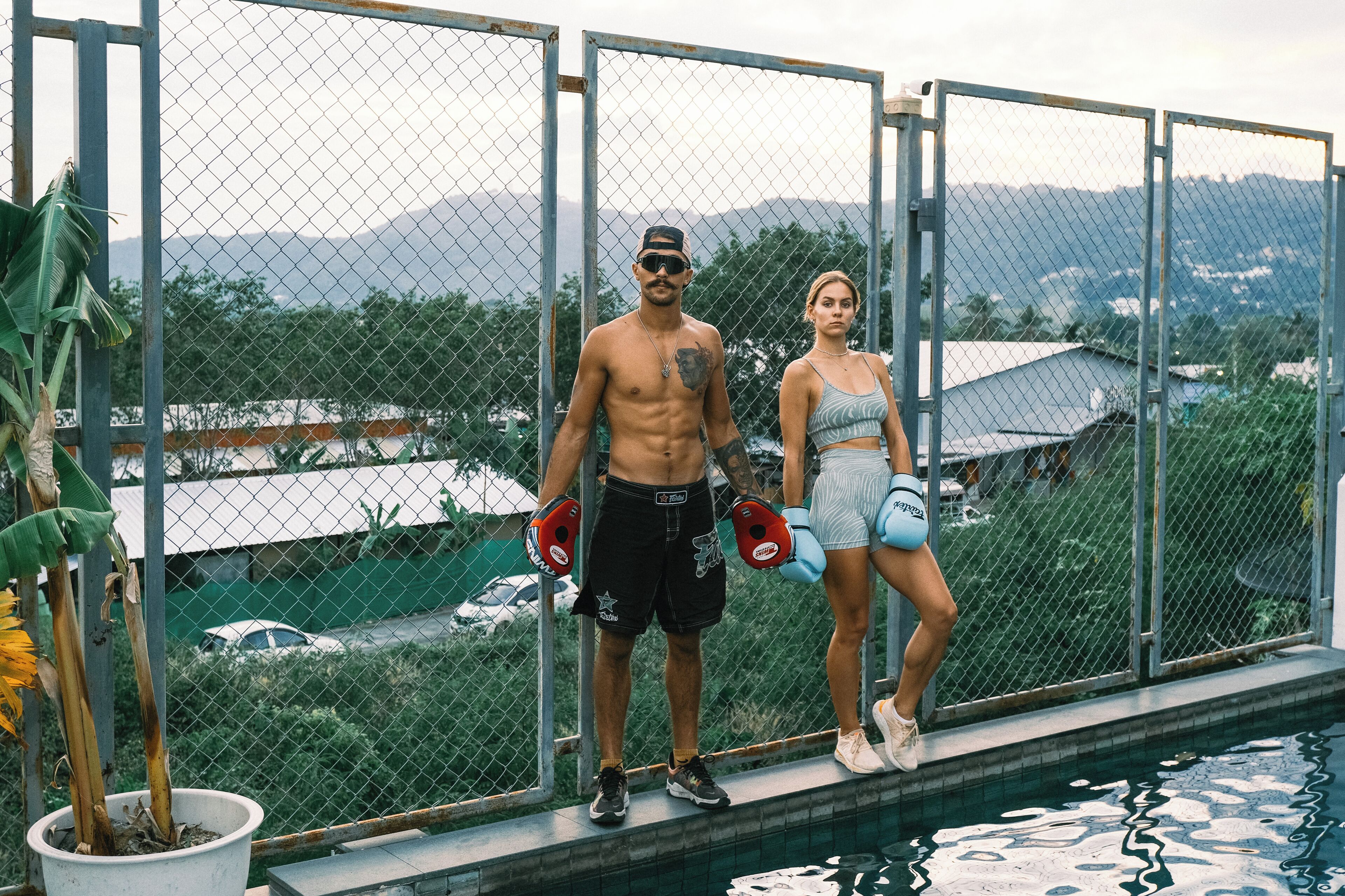 Dos personas junto a una piscina con vistas a un paisaje montañoso.
