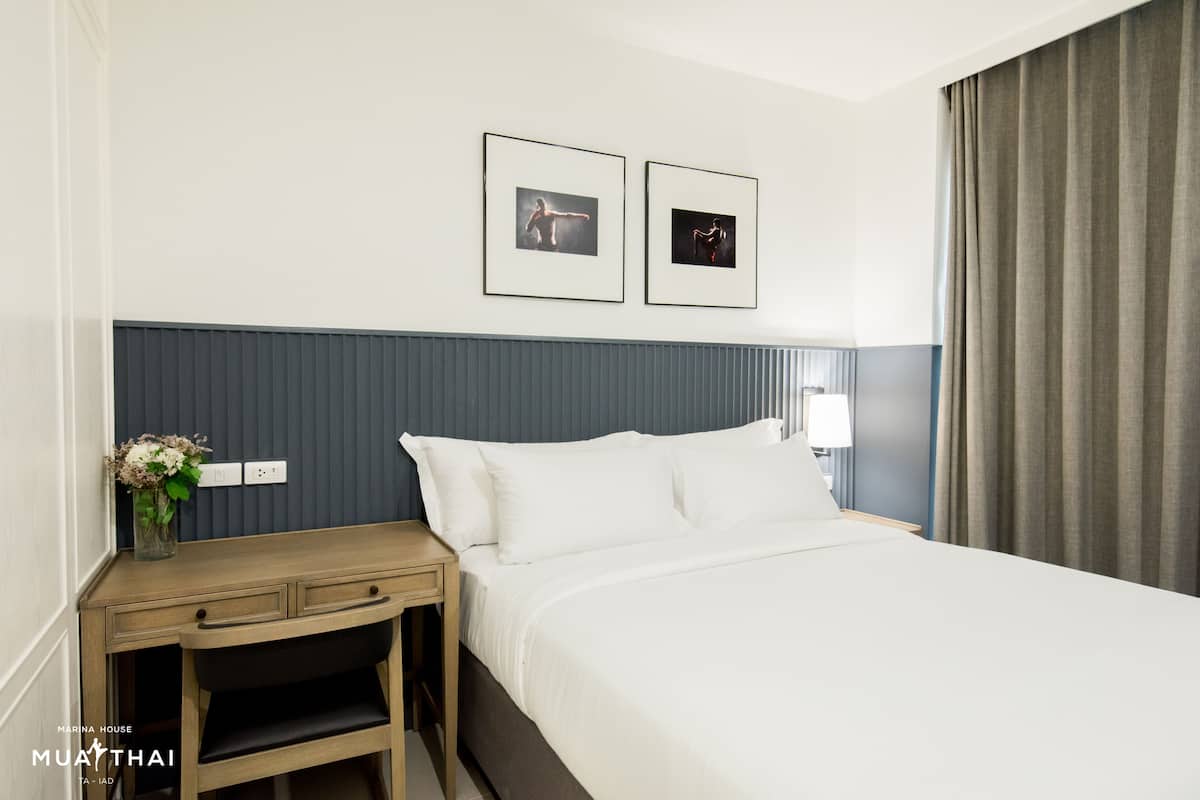 A hotel room with a bed, a nightstand, a lamp, and two framed pictures on the wall.