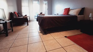 Une chambre d’hôtel avec un lit, un bureau, une chaise et une fenêtre avec des rideaux.