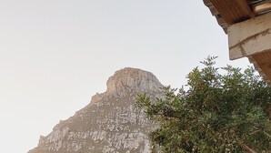 Une montagne au sommet rocheux, entourée d’une végétation clairsemée et dominée par un ciel dégagé.