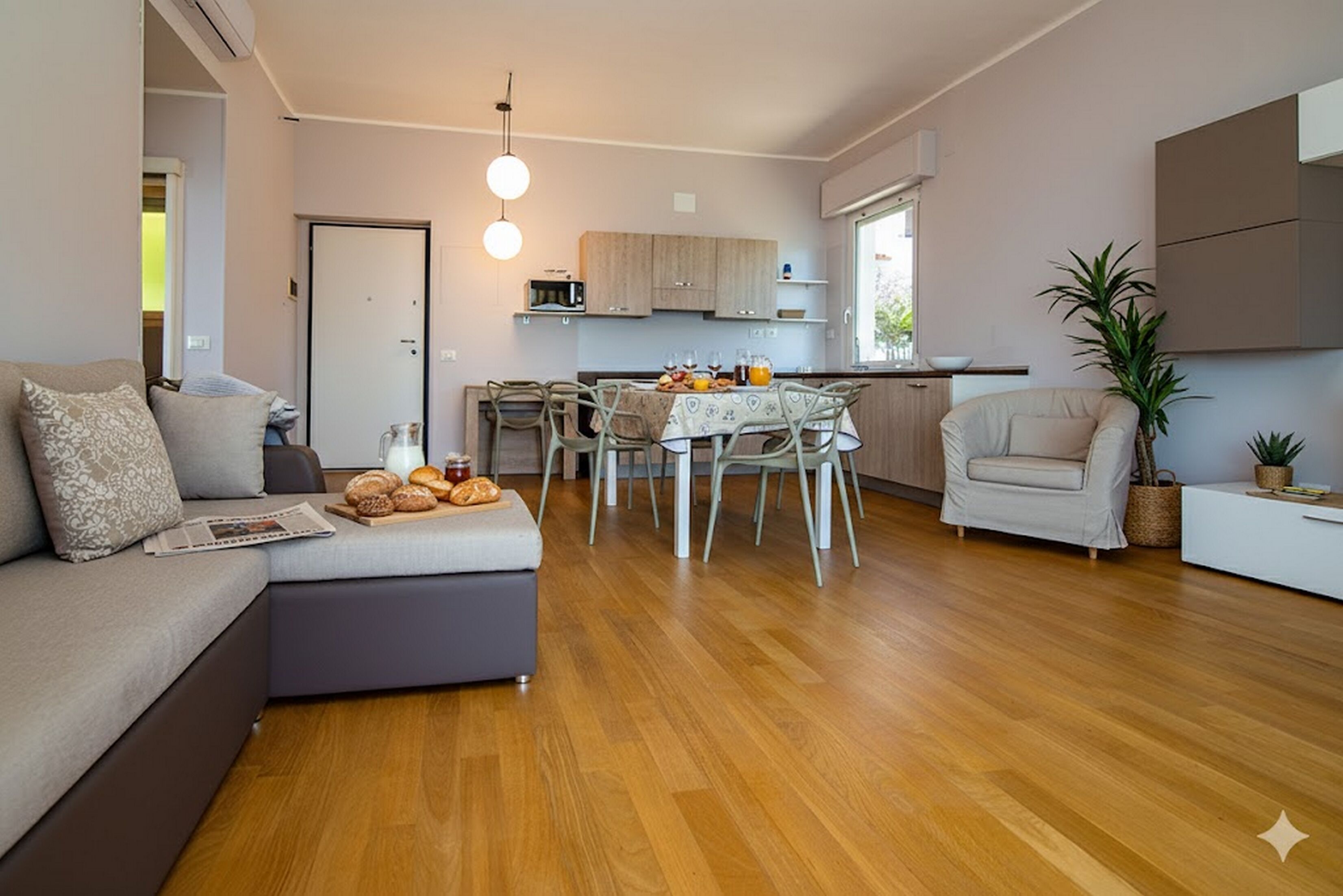Un salon moderne comprenant un canapé, une table à manger avec des chaises et un coin cuisine avec des placards et un four à micro-ondes.