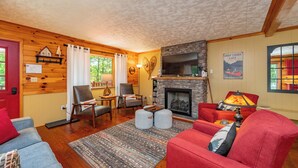 Ein gemütliches Wohnzimmer mit Kamin, Holzwänden und einem roten Sofa.