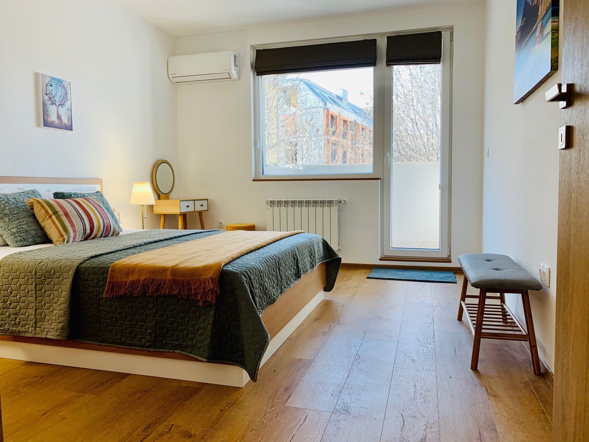 Une chambre à coucher avec un lit, une table de chevet, une lampe et un banc.