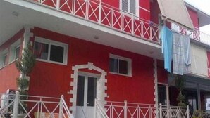 A red building with white railings and a door. - Hotel Number One (Gjirokaster)