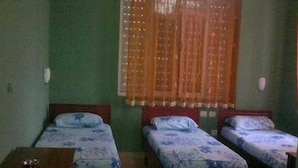 A room with two single beds, a small wooden table, and a window with a curtain. - Hotel Number One (Gjirokaster)