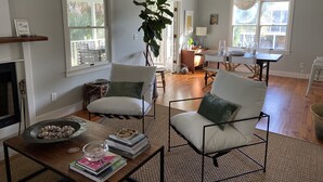 A spacious living room with a fireplace, large windows, and a dining area. - Fun Beach House (Sullivans Island)