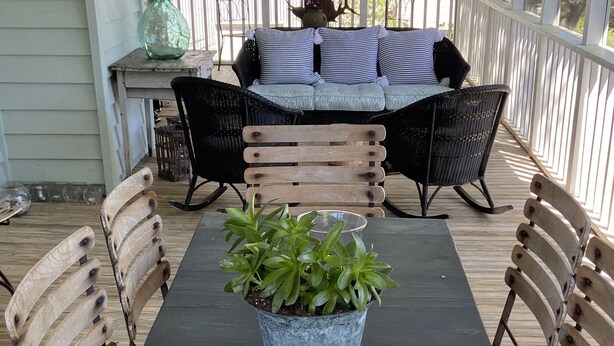 A covered outdoor dining area with a table, chairs, a potted plant, and a candle. - Fun Beach House (Sullivans Island)