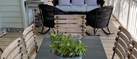 Un espacio de comedor al aire libre techado con una mesa, sillas, una planta en maceta y una vela.