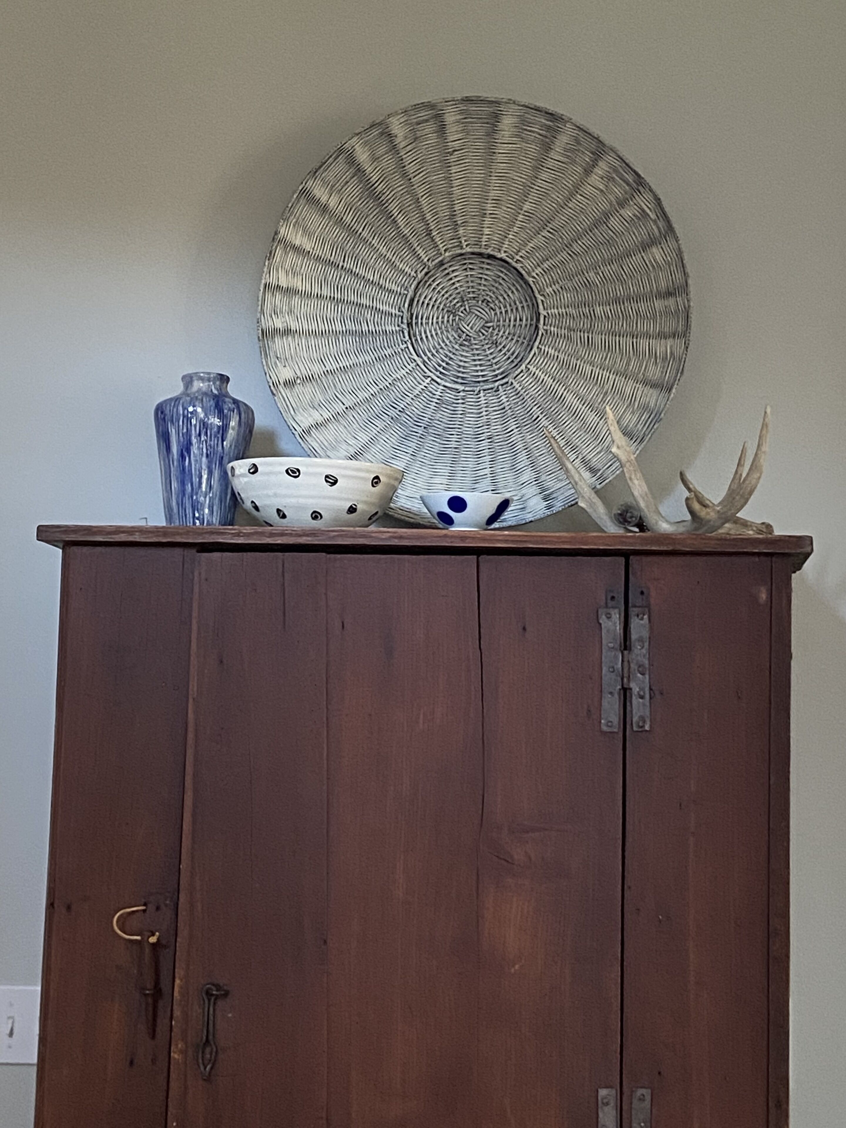 Un meuble en bois surmonté d’une plaque décorative et de bois de cerf.