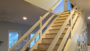 A staircase with white railings and wooden steps, leading to a landing with a skylight. - Fun Beach House (Sullivans Island)