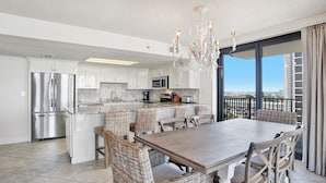 A modern kitchen with a central island, stainless steel appliances, and a dining area with wicker chairs.