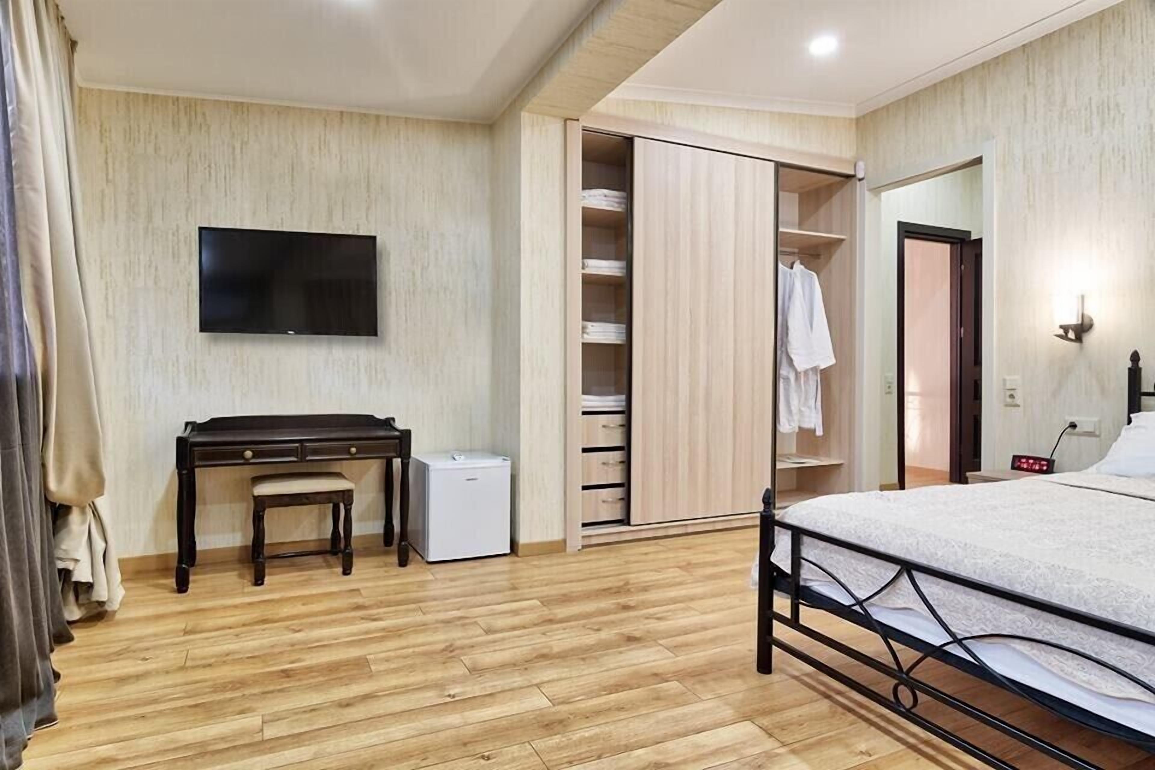 A bedroom with a bed, a desk, a TV, and a wardrobe.