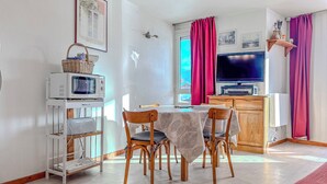 A small, bright kitchen with a dining table, chairs, a microwave, a toaster, and a television. - #AH3 | The Snow White ❄ (Huez)
