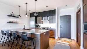 Une cuisine moderne dotée d’un îlot central, de tabourets de bar et de luminaires suspendus.