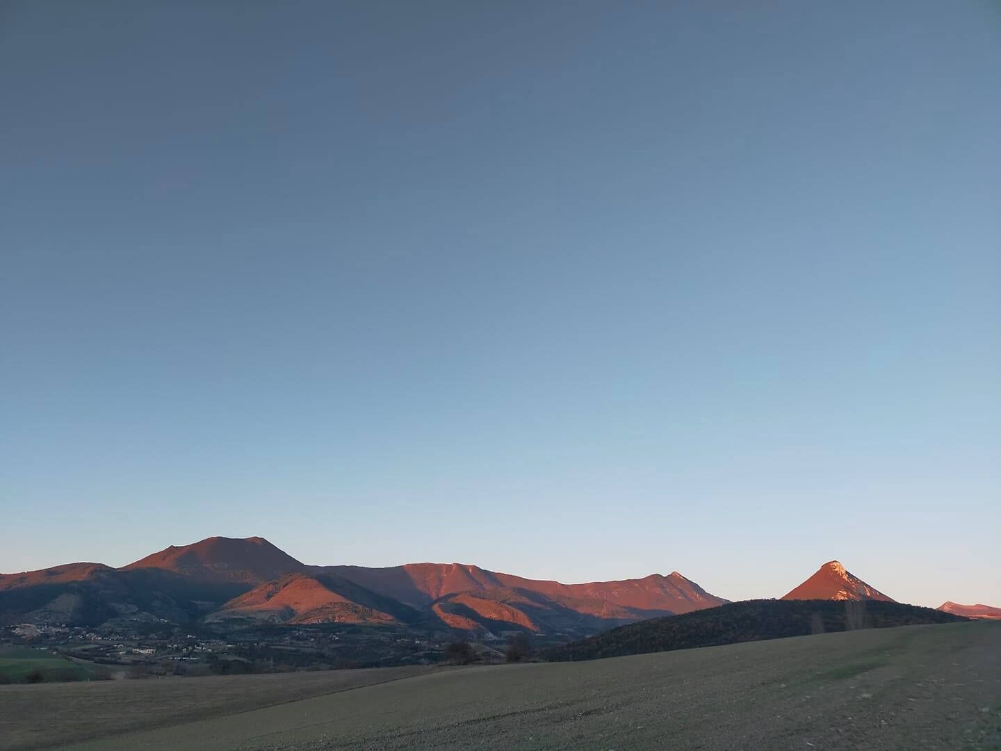 Un paysage rural avec des montagnes et un ciel dégagé.