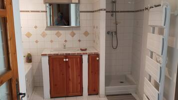 Een bad/douchecombinatie, een haardroger, handdoeken, toiletpapier