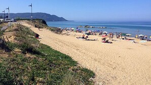 A beach with people, umbrellas, and a clear sky.