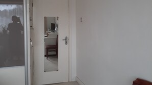 Ein Zimmer mit einer weißen Tür, einem Spiegel, einem Stuhl und einem kleinen Tisch.