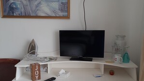 Eine weiße Unterhaltungseinrichtung mit einem Flachbildfernseher, einer Fernbedienung, einer Taschentuchbox und einem Dekorationswürfel.