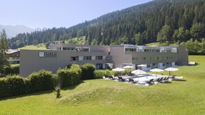 A modern building with a sign reading "Tavern Residence." It features a swimming pool with lounge chairs and umbrellas, surrounded by a well-maintained lawn. - Superior apartment with 1 bedroom & summer pool (Radstadt)