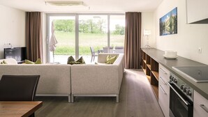 A modern kitchen with a built-in oven and a dining area with a table and chairs. - Superior apartment with 2 bedrooms & summer pool (Radstadt)