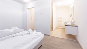Een moderne hotelkamer met een bed, een badkamer met een wastafel en spiegel, en een inloopkast.