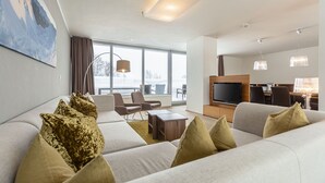 Een moderne woonkamer met een bank, stoelen, een salontafel en een televisie.