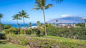 A tropical resort with palm trees, a view of the ocean, and a mountain in the background. - Maui Kamaole #J-119 Oceanview, Ground Flr, Great Location, near beach, A/C (Kihei)