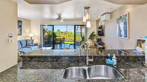 A kitchen with a granite countertop, stainless steel sink, and a ceiling fan. - Maui Kamaole #J-119 Oceanview, Ground Flr, Great Location, near beach, A/C (Kihei)