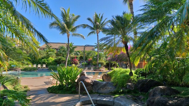 A resort pool area with a small water feature, palm trees, and lounge chairs. - Maui Kamaole #J-119 Oceanview, Ground Flr, Great Location, near beach, A/C (Kihei)
