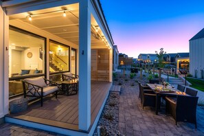 Ein modernes Haus mit überdachter Terrasse, Gartenmöbeln und einem hellen Innenraum.