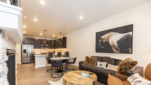A modern living room with a round coffee table, a sofa, and a dining area with chairs.