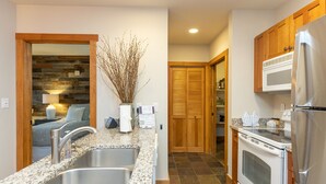 A kitchen with granite countertops, stainless steel sinks, wooden cabinets, a built-in oven, and a refrigerator. - River Run Village Condo is Only a Short Walk to Gondola, Shops and Dining! (Keystone)