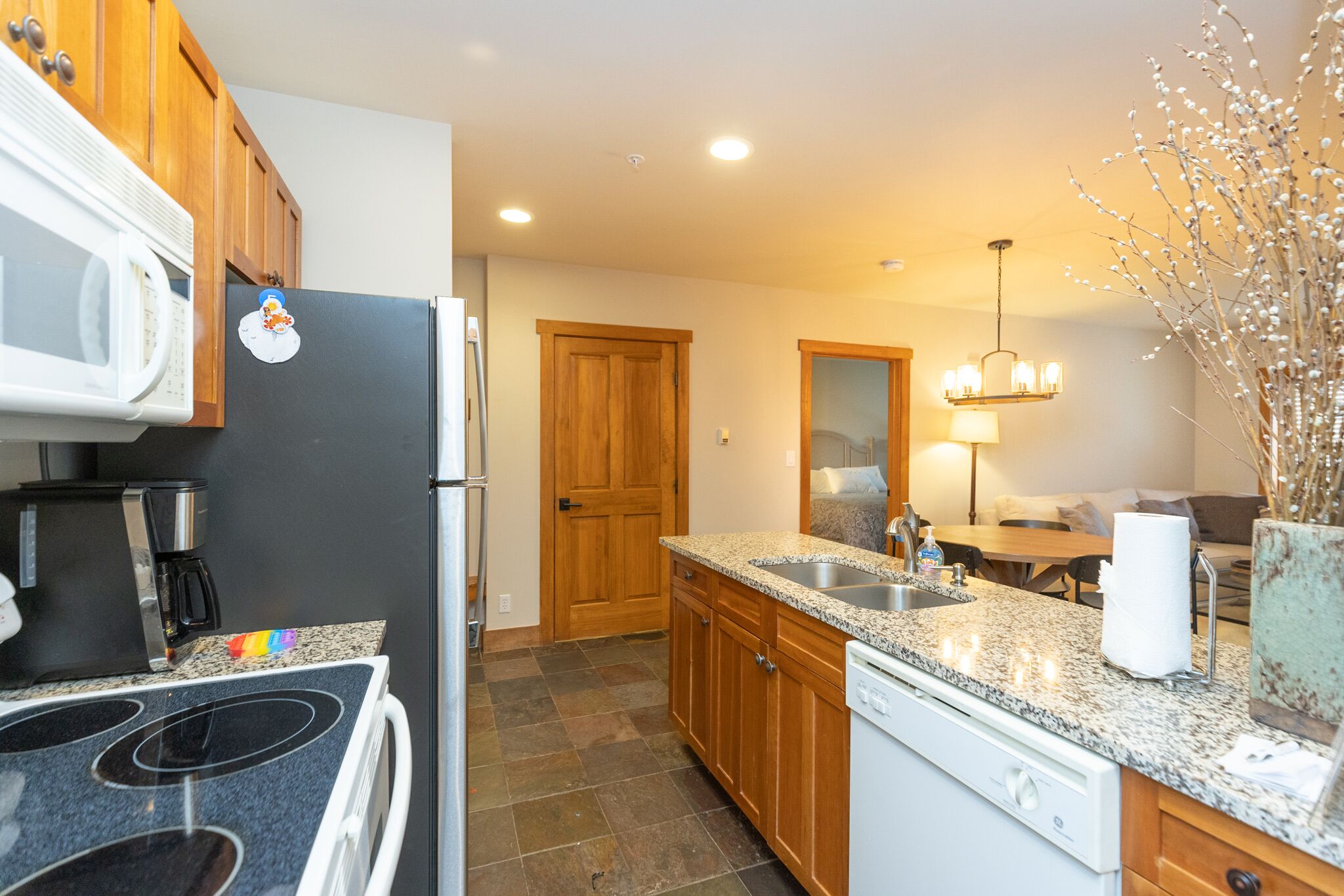 A modern kitchen with granite countertops, a built-in dishwasher, and wooden cabinets.
