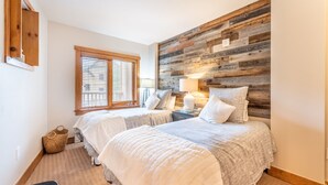 A bedroom with two beds, a wooden headboard, a window with blinds, a bedside lamp, and a woven basket. - River Run Village Condo is Only a Short Walk to Gondola, Shops and Dining! (Keystone)