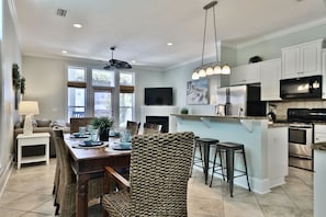 Enjoy meals in the kitchen with a central island, microwave, and stainless steel refrigerator. Dine in the adjacent area with a wooden table and wicker chairs.