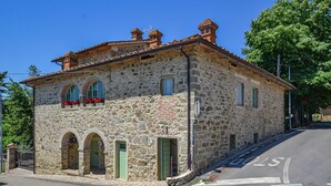 Un edificio in pietra con tetto a tegole, finestre ad arco e un piccolo balcone fiorito.