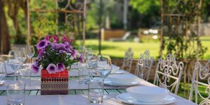 A table set for a meal with white plates, bowls, and glasses, and a colorful vase with purple flowers. - Tuscan Villa with Private Park and Hydromassage Mini-pool (Capolona)