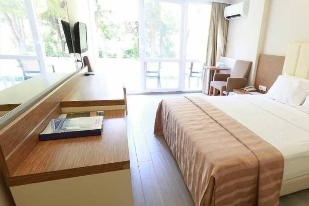 A hotel room with a bed, a desk, a chair, and a TV.