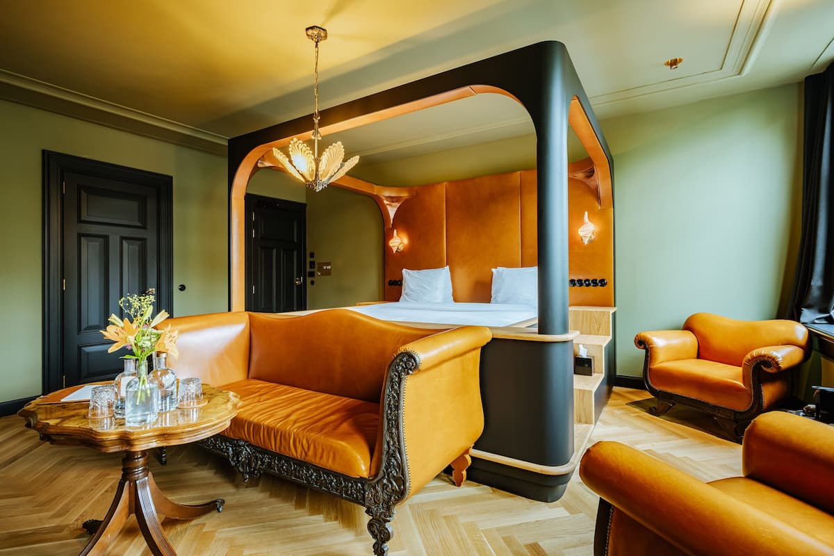 A hotel room with a large bed, a sitting area with a table, and a chair.