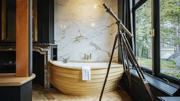 A modern bathroom with a freestanding bathtub, marble wall, and a tripod in the corner.