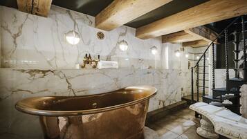 Relax in a spacious bathroom with a bathtub, marble walls, and a wooden ceiling.