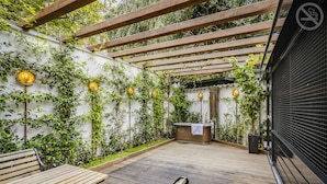 A wooden deck with a bench, a hot tub, and a pergola. - Hotel The Noblemen (Amsterdam)