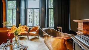 A room with a large window, a vintage bathtub, and two ornate chairs. - Hotel The Noblemen (Amsterdam)