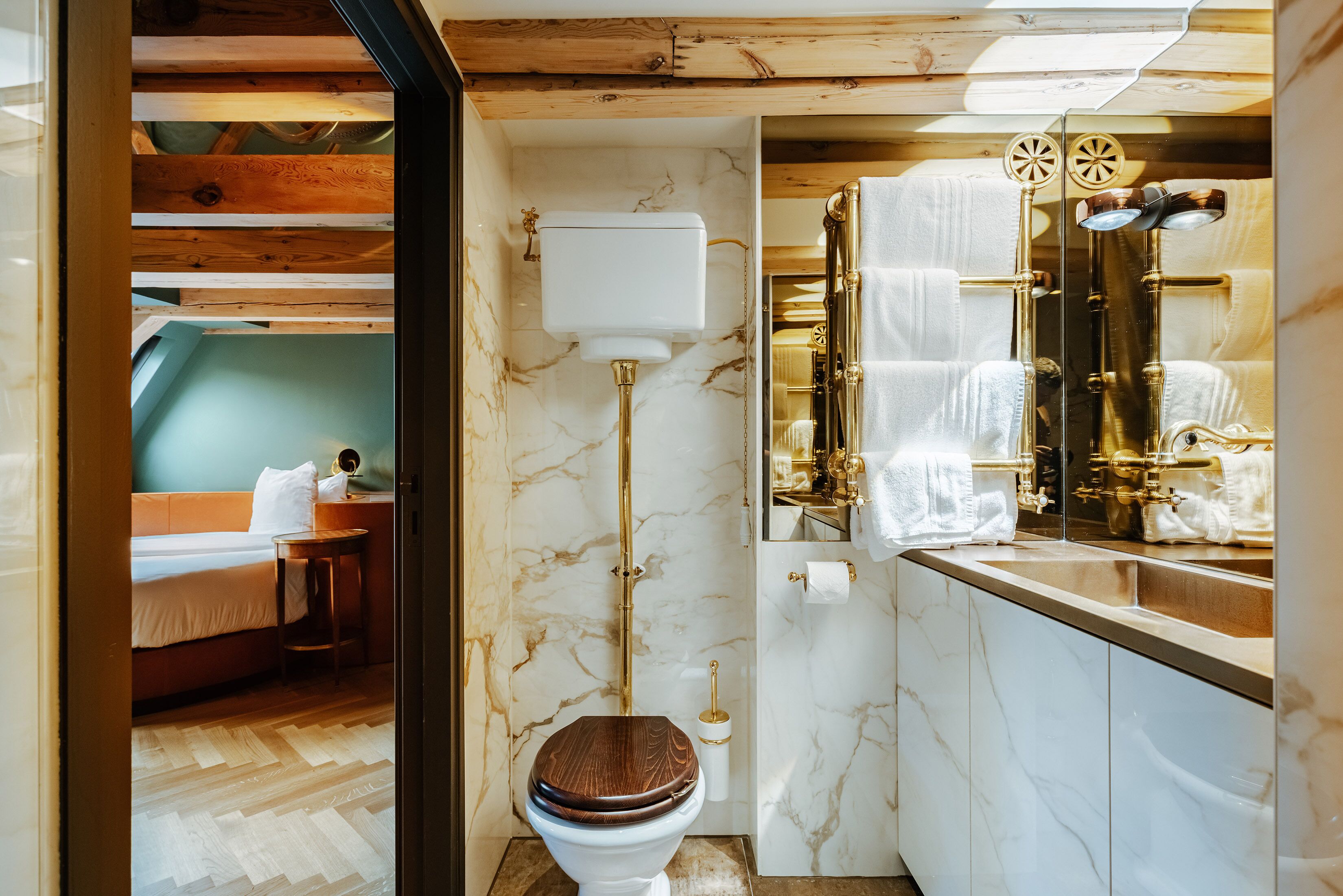 Un bagno con il water, pareti in marmo e soffitto in legno.