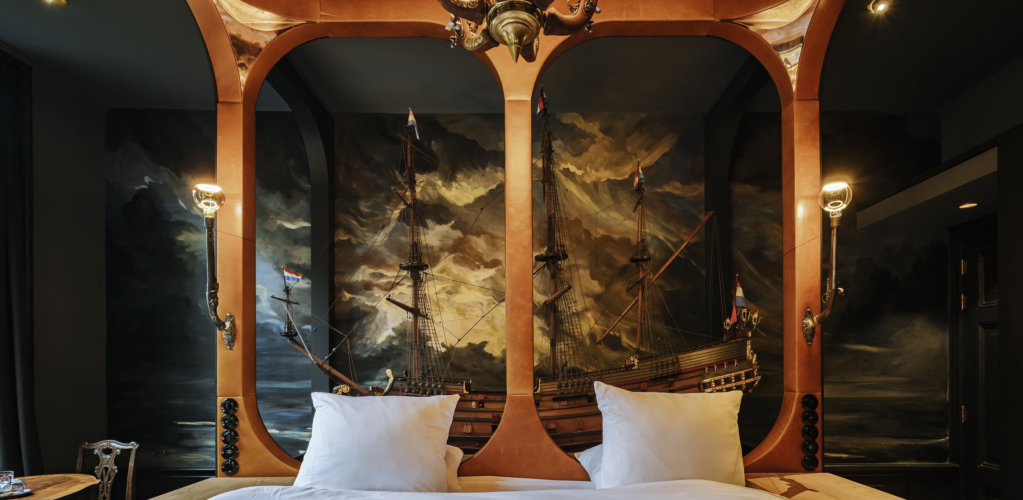 Camera da letto lussuosa con un letto grande, una testiera in legno finemente decorata e un affresco raffigurante una nave che solca mari in tempesta.