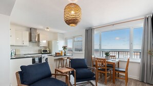 Una cocina moderna con armarios blancos, una campana extractora de acero inoxidable y un comedor con mesa y sillas.