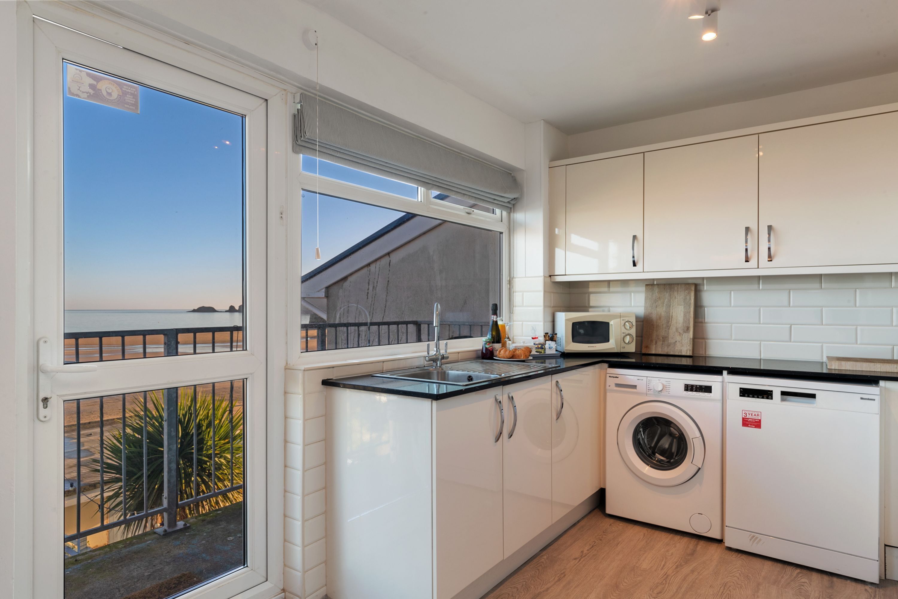 A compact kitchen with a washing machine, a microwave, and a sink.